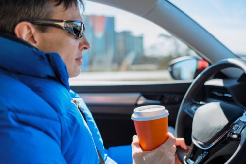 man holds drink in disposable paper cup while driving - junk food stock pictures, royalty-free photos & images