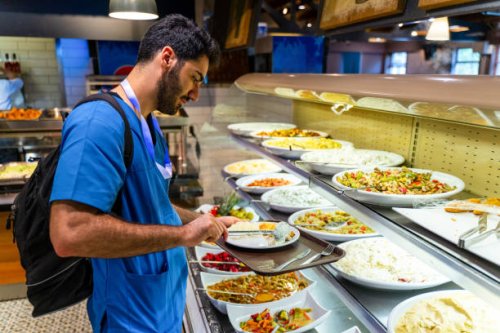 man in medical scrubs eating at a buffet style cafeteria - food stock pictures, royalty-free photos & images
