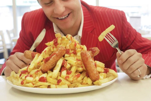 man in red suit eating large plate of sausages and chips - junk food stock pictures, royalty-free photos & images