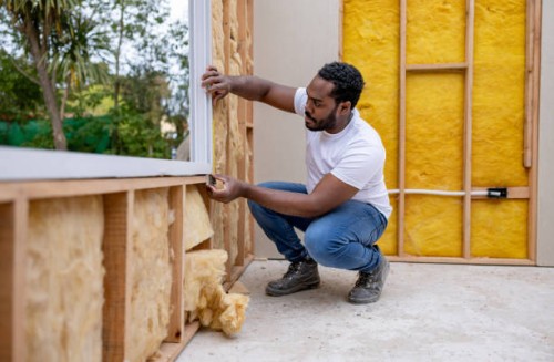 man installing a window while working as a volunteer building a house - home decoration stockfoto's en -beelden