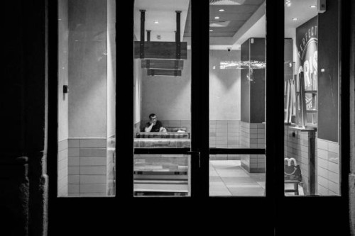 Man is sitting at a fast food restaurant in the city center of Milan, Italy, during the Christmas period, on December 21, 2023.