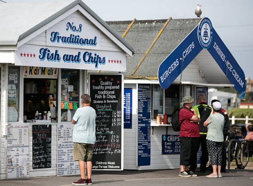 Man looks at the menu at a fish and chip takeaway hut as visitors take advantage of the fine weather at West Bay on September 1, 2016 in Dorset,...