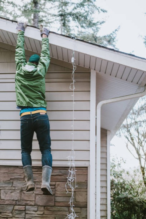 man loses ladder while hanging christmas lights on house - home decoration stock pictures, royalty-free photos & images