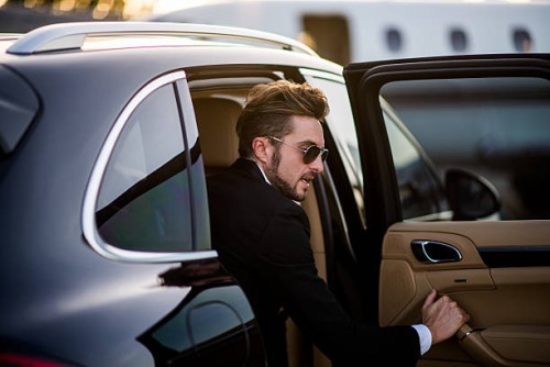 man on the airport opening car door - fashion stock pictures, royalty-free photos & images