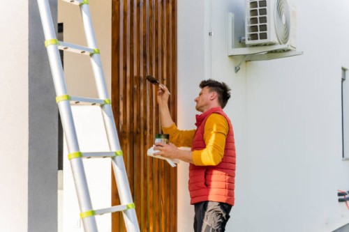man painting wooden columns of modern villa while standing by ladder - home decoration stock pictures, royalty-free photos & images