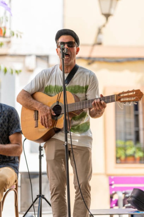 man playing a guitar and singing while performing on an outdoor stage. - concert stock pictures, royalty-free photos & images