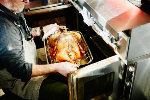 man pulling cooked turkey out of oven - food stock pictures, royalty-free photos & images