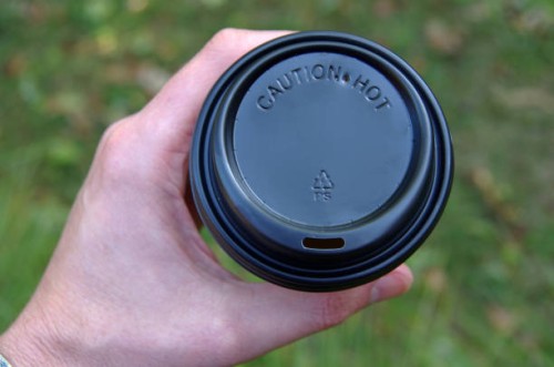 man's hand holding a disposable coffee cup with a black plastic lid - junk food stock pictures, royalty-free photos & images