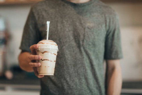 man's hand holding plastic cup of coffee delicacy - junk food stock pictures, royalty-free photos & images