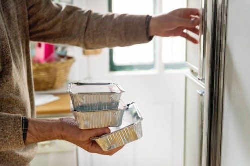 man's hand opening refrigerator to stack takeout meal. - junk food stock pictures, royalty-free photos & images
