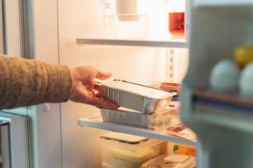 man's hand taking takeout meal out of refrigerator. - junk food stock pictures, royalty-free photos & images