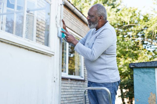 man scraping wall of house during renovation - home decoration stock pictures, royalty-free photos & images