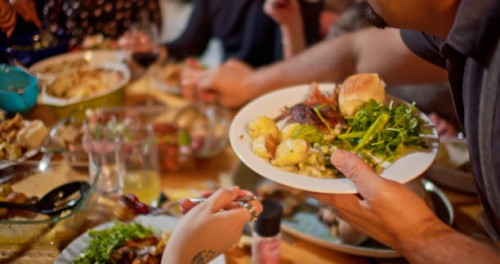 man serving himself at friendsgiving potluck dinner - food stock pictures, royalty-free photos & images