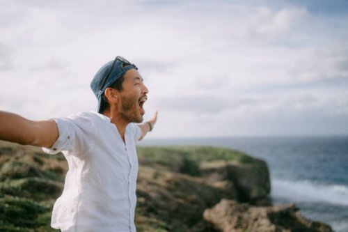 man shouting on top of cliff by sea - travel stock pictures, royalty-free photos & images