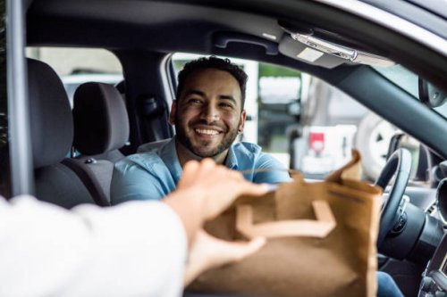 man smiles while picking up curbside order - junk food stock pictures, royalty-free photos & images
