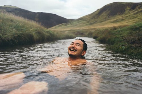 man soaking in natural hot spring surrounded by nature in iceland - travel stock pictures, royalty-free photos & images