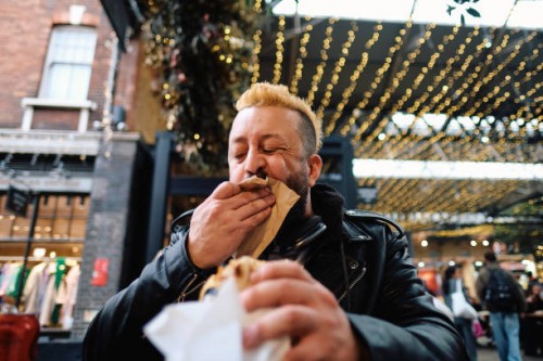 man spontaneously cleans mouth with napkin while enjoying food market fare. - food stock pictures, royalty-free photos & images