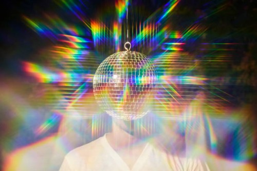man standing behind a disco ball as if it is his head with reflective psychedelic colors. - fashion stock pictures, royalty-free photos & images