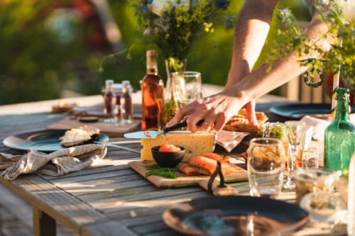 man taking a slice of cheese at midsummer dinner - garden decoration stock pictures, royalty-free photos & images