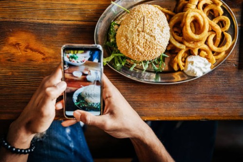 man talking picture of burger with smartphone - junk food stock pictures, royalty-free photos & images