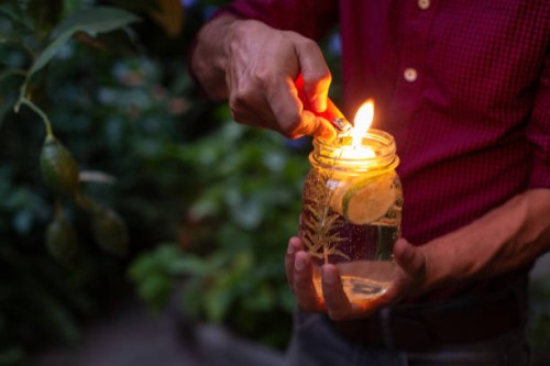 man using lemon scented floating candle as a natural mosquito repellant - garden decoration stock pictures, royalty-free photos & images