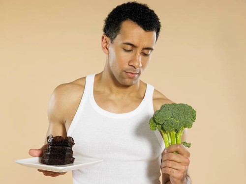 man with broccoli and chocolate cake - junk food stock pictures, royalty-free photos & images