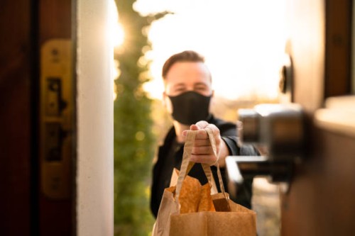 man with face mask delivering food - junk food stock pictures, royalty-free photos & images