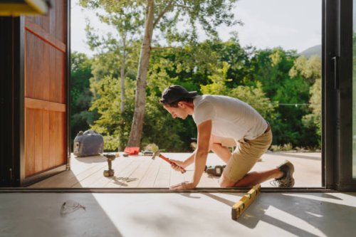 man working on wooden decking in front of a cabin house - home decoration stock pictures, royalty-free photos & images