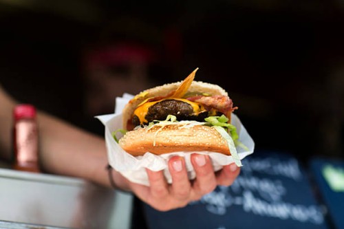 mans hand serving hamburger from fast food van - junk food stock pictures, royalty-free photos & images