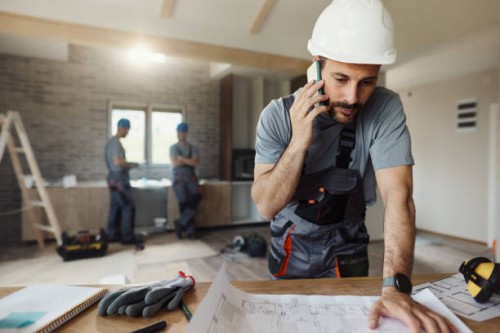 manual worker talking on cell phone during home renovation process. - home decoration stock-fotos und bilder