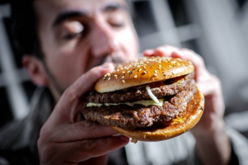 March 2025, Bremen: ILLUSTRATION - A man bites into a burger. Photo: Sina Schuldt/dpa