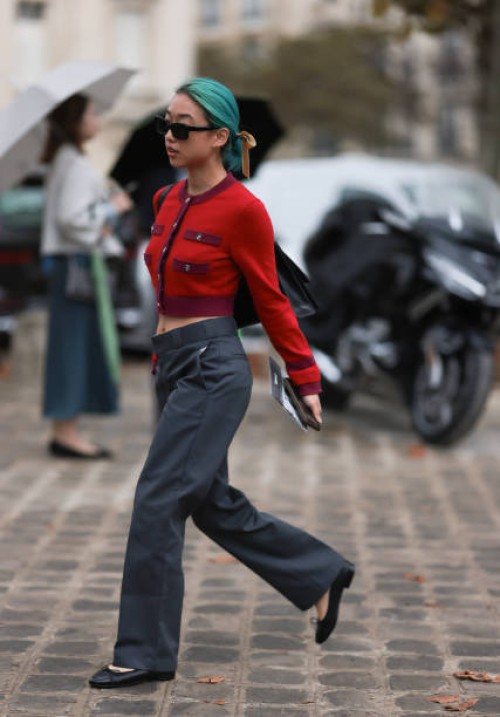 Margaret Zhang is seen outside Chanel show wearing black Chanel sunnies, red and lilac Chanel cropped Cardigan, low waist grey pants and black ballet...
