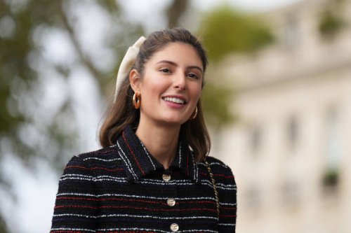 Maria de la Orden wears a bow tie hair bun, golden earrings, a dark blue red and white striped long tweed dress, outside Chanel, during the...