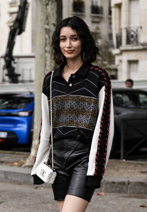 Maria Shindo is seen wearing a Chanel print top, black faux leather shorts and a white Chanel mini-bag outside the Chanel show during the Womenswear...