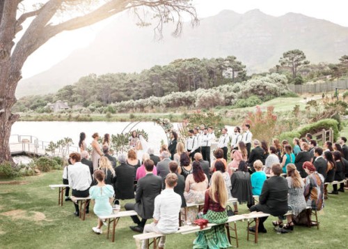 mariage, nature et groupe de famille et d’amis à la cérémonie dans un jardin du lac pour la célébration. l’amour, le plein air et les invités qui regardent un couple se marier lors d’un événement de luxe, élégant et de mariag