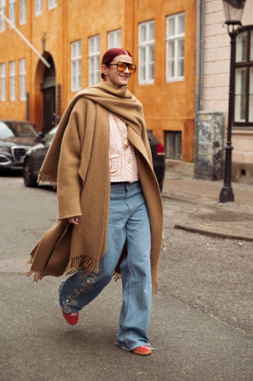 Marianne Theodorsen wears wide jeans, a brown coat, and orange sunglasses outside Lovechild 1979 during the Copenhagen Fashion Week AW24 on January...