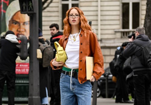 Marie Gaguech is seen wearing an orange Miu Miu jacket, white t-shirt, blue jeans and yellow bag outside the Miu Miu show during the Womenswear...