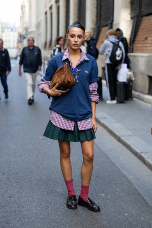 Marina Suarez wears brown suede bag, navy polo, green skirt outside Lacoste during Womenswear Spring/Summer 2025 as part of Paris Fashion Week on...