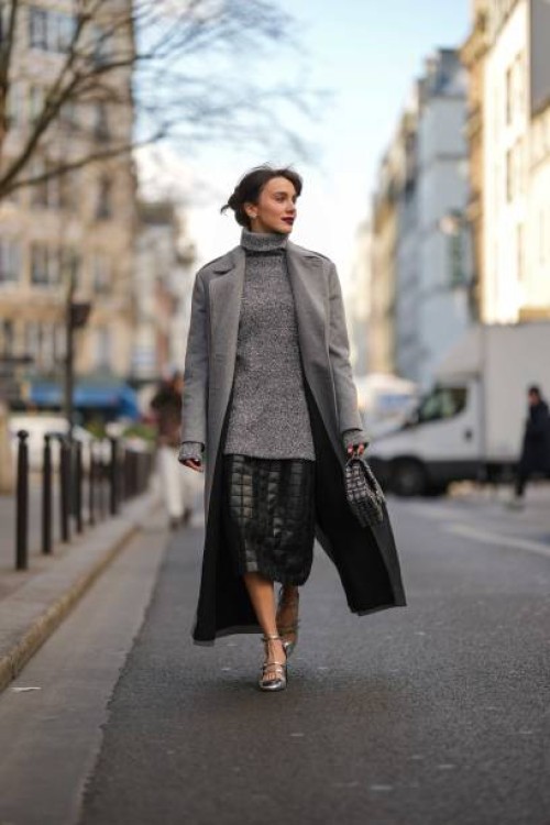 Mary Leest wears a gray wool turtleneck oversized pullover, a pale gray glitter wool long coat, a black shiny leather embossed checkered pattern...