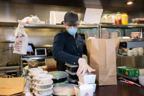 masked and gloved man in restaurant kitchen packaging food for delivery during covid-19 outbreak - junk food stock pictures, royalty-free photos & images