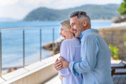 mature couple embracing on a waterfront balcony. - travel stock pictures, royalty-free photos & images