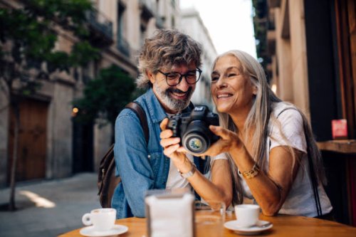 mature couple on vacation enjoying at the cafe and watching their photos - travel stock pictures, royalty-free photos & images