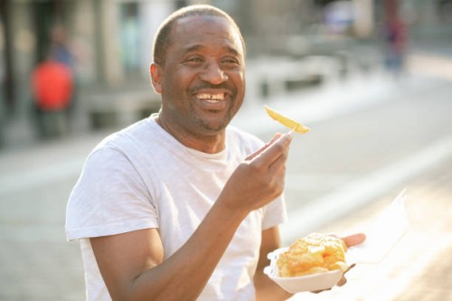 mature male eating fish and chips - junk food stock pictures, royalty-free photos & images