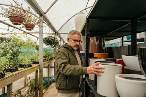 mature man choosing flower pots in flower shop - garden decoration stock pictures, royalty-free photos & images