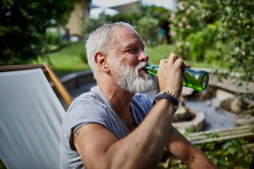 mature man drinking beer from bottle in garden - garden decoration photos et images de collection
