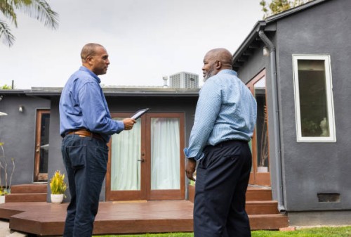 mature salesman holding digital tablet while discussing with male customer outside house - home decoration stock pictures, royalty-free photos & images