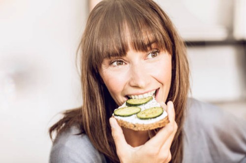 mature woman eating healthy cucumber bread - food photos et images de collection
