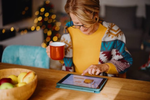 mature woman using digital tablet for online christmas shopping - home decoration stock pictures, royalty-free photos & images