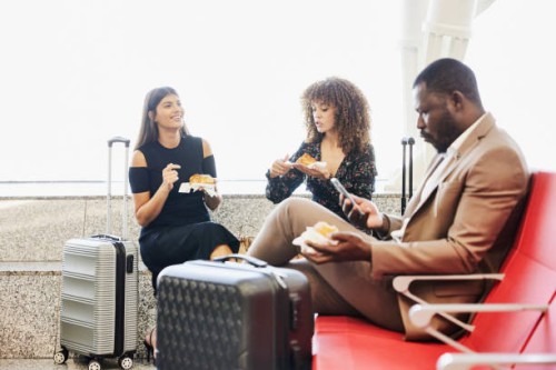 medium shot of friends waiting for flight in departure area of airport - food stock pictures, royalty-free photos & images