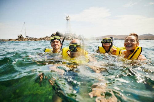 medium shot of smiling family on snorkeling tour in tropical ocean - travel stock pictures, royalty-free photos & images